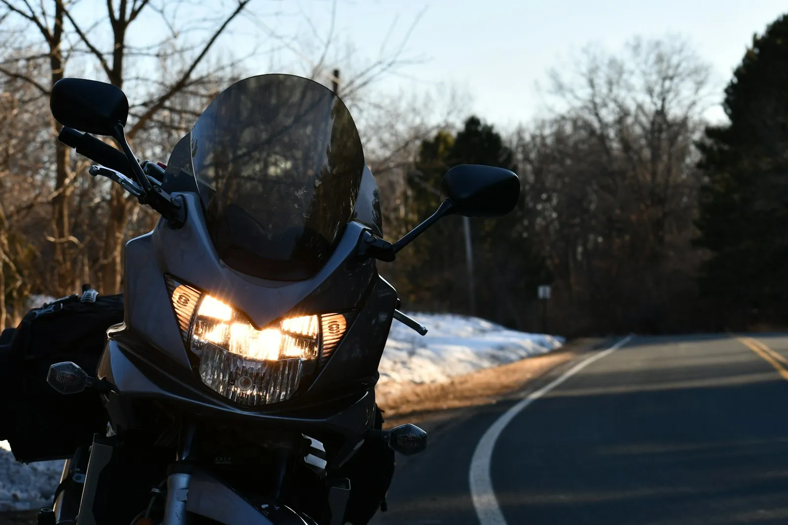 motorcycle riding winding country road at sunrise